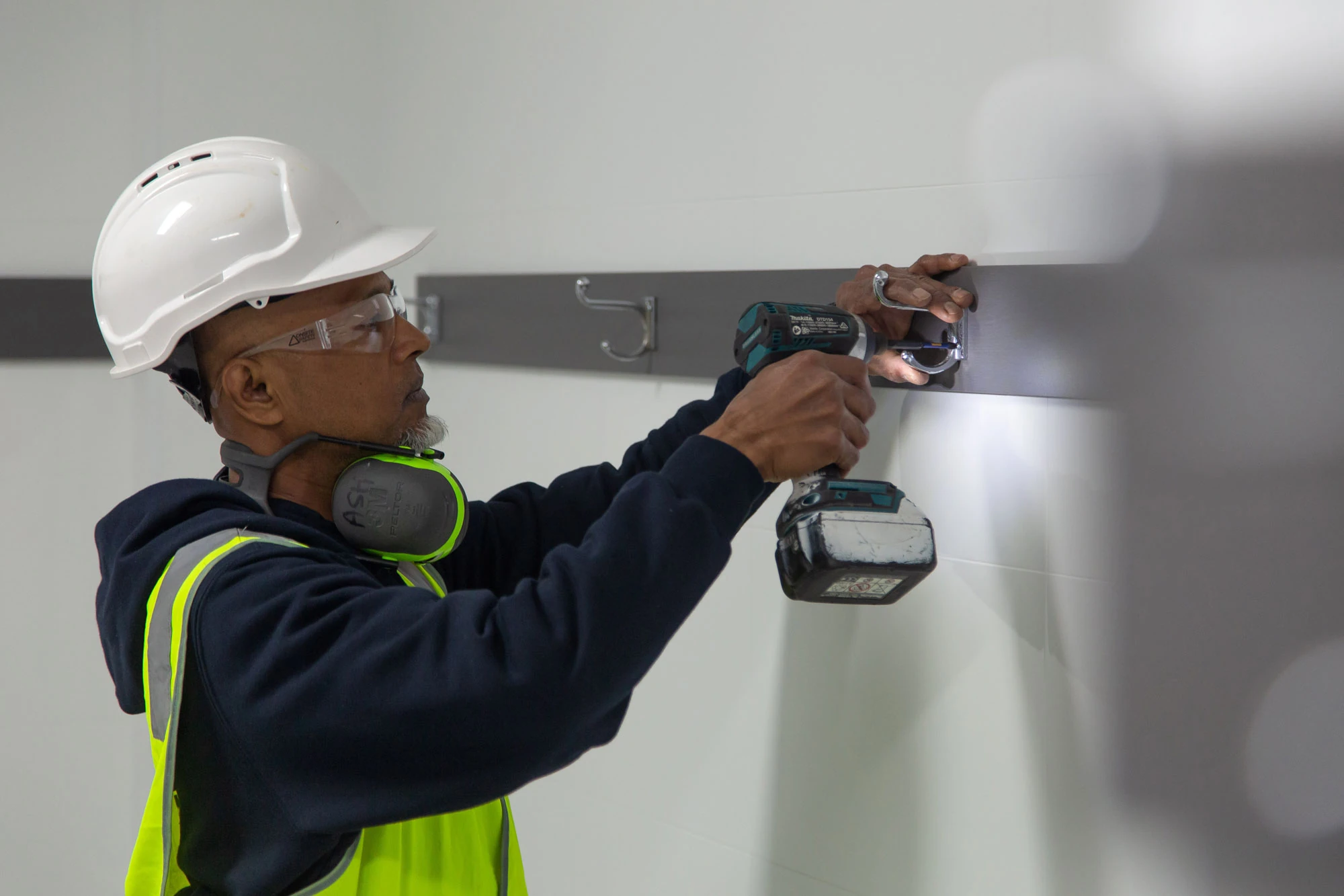 Maintenance worker using a drill to install a wall fitting